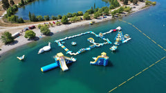 Large inflatable water park by Soft Summits with slides, climbing areas, and splash zones for commercial outdoor fun.