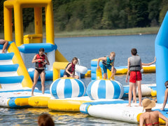 Large inflatable water park by Soft Summits featuring slides, climbing areas, and water features for commercial outdoor fun.
