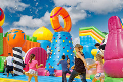 Colorful themed inflatable obstacle course by Soft Summits with multiple slides, tunnels, and climbing sections for outdoor fun.