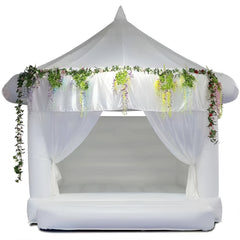 A stylish white wedding bouncy castle by Soft Summits, decorated with greenery for a unique and sophisticated event touch.