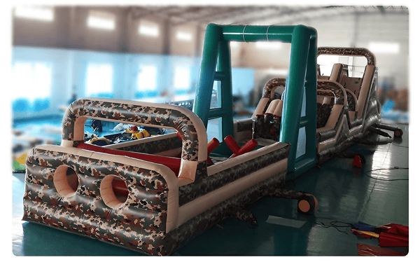 Soft Summits commercial size inflatable obstacle course in camouflage with climbing walls, slides, and tunnels for outdoor fun.