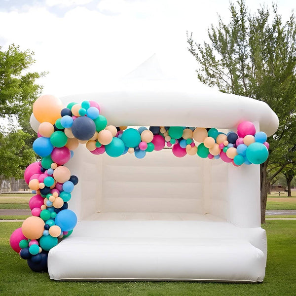 White commercial-grade wedding bouncy house by Soft Summits with balloon decorations, ideal for wedding celebrations.